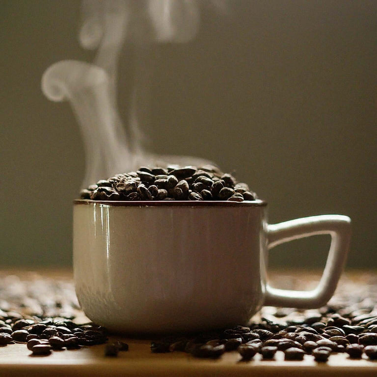 A steaming cup filled with coffee beans, highlighting the rich aroma and bold flavor of Brazil Pearl coffee.