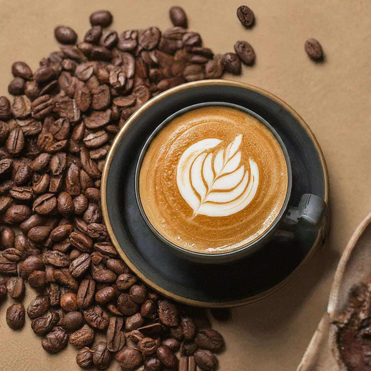 A cup of hazelnut coffee artfully decorated with latte art, surrounded by fresh coffee beans.