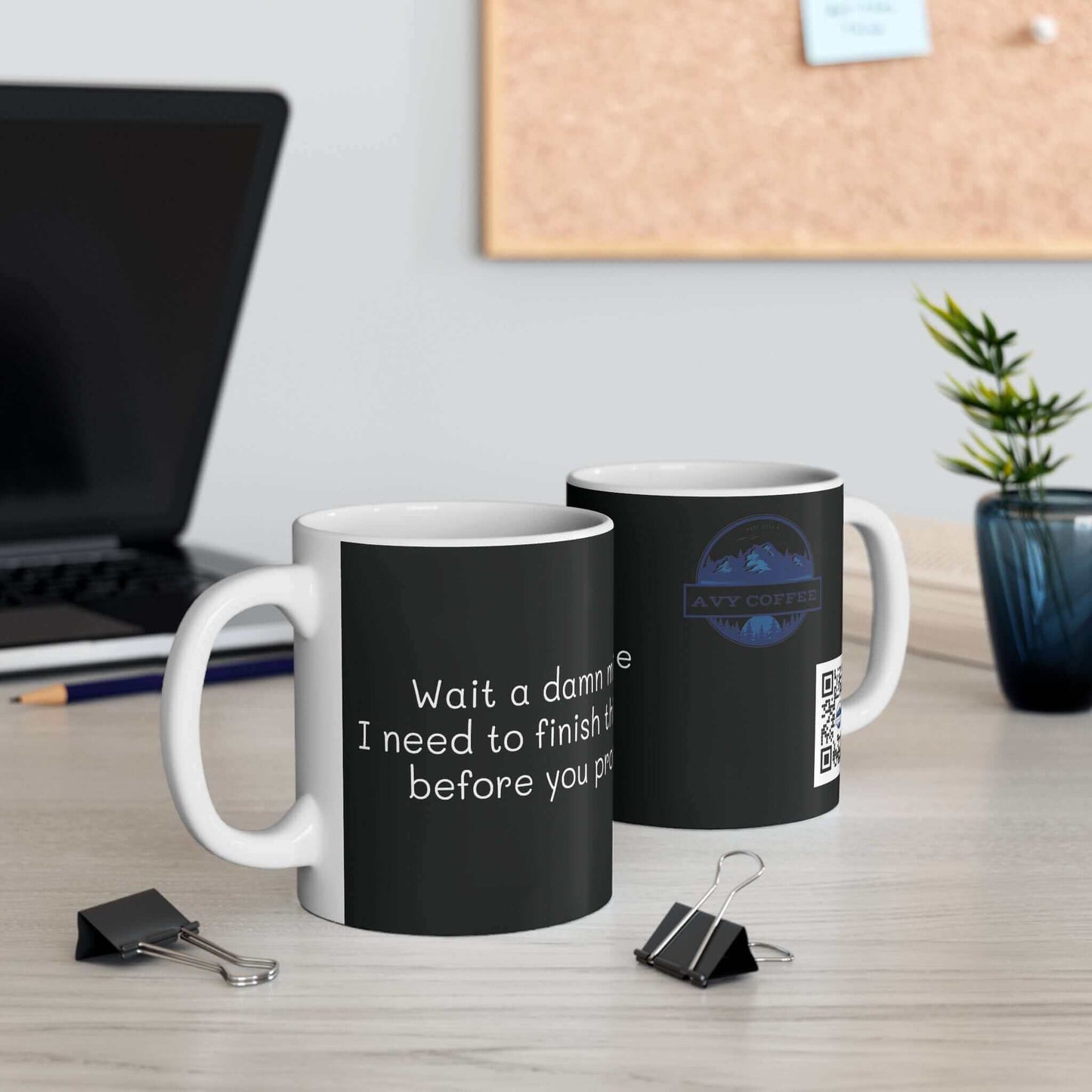 Two "Wait a damn minute. 11oz Mug" ceramic mugs placed on an office desk, perfect for coffee lovers.