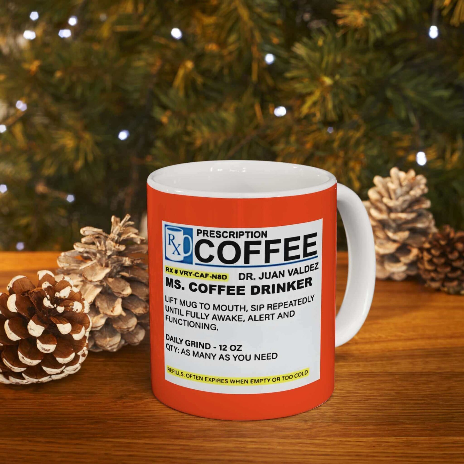 Red Prescription Coffee Mug - For Her (11oz, 15oz) displayed on a wooden table with Christmas lights and pine cones in the background.