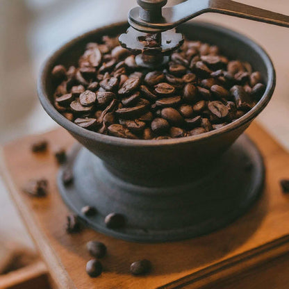 Dark roast coffee beans in vintage grinder, perfect for 6 Bean Blend espresso.