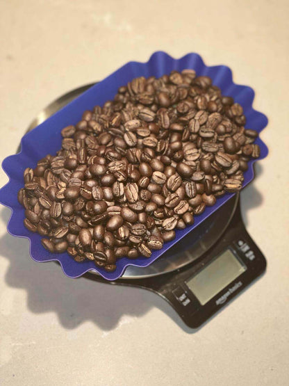 House Blend coffee beans showcasing rich, roasted texture in a blue container on a digital scale.