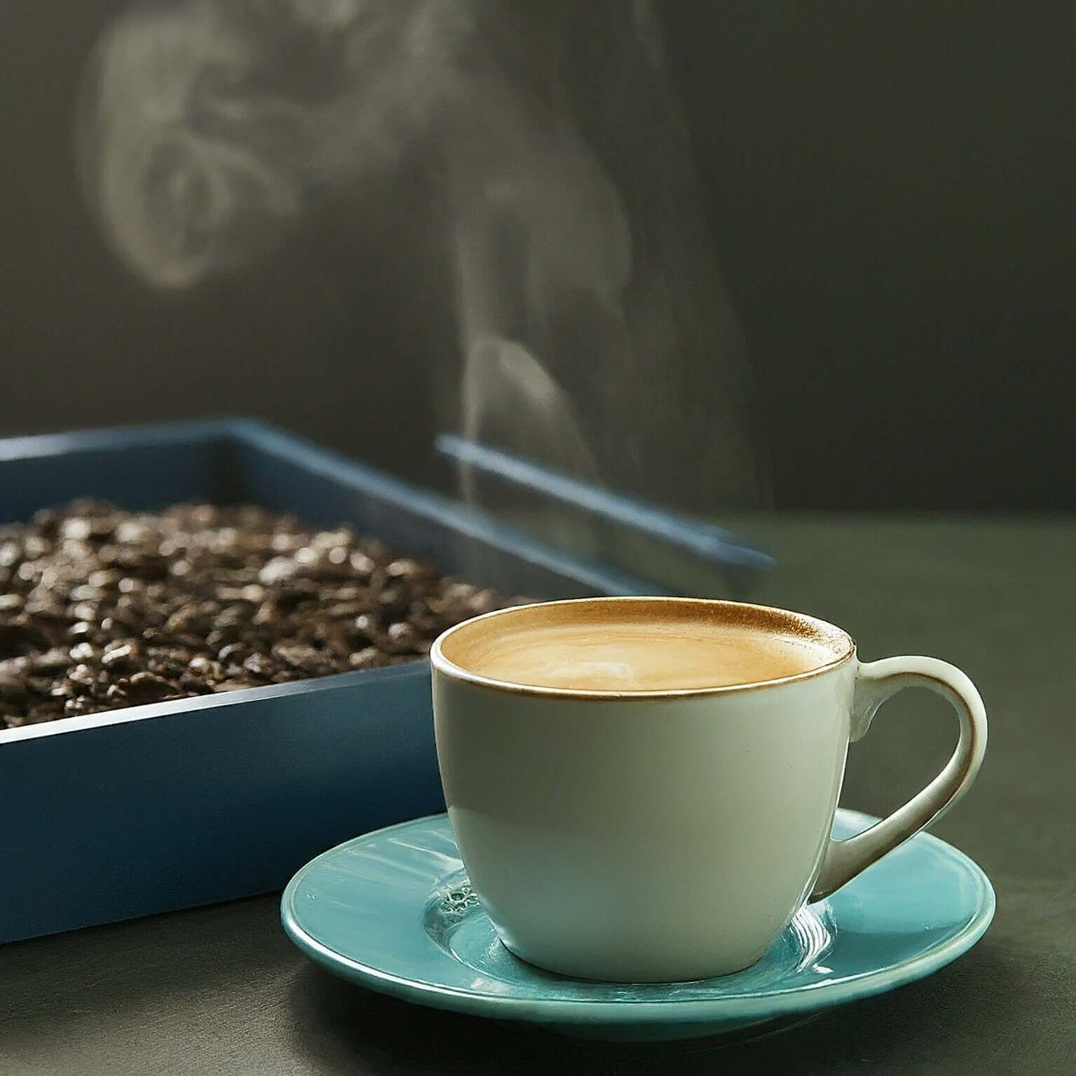 Steaming cup of Gourmet Fancy Tanzania coffee with coffee beans in the background