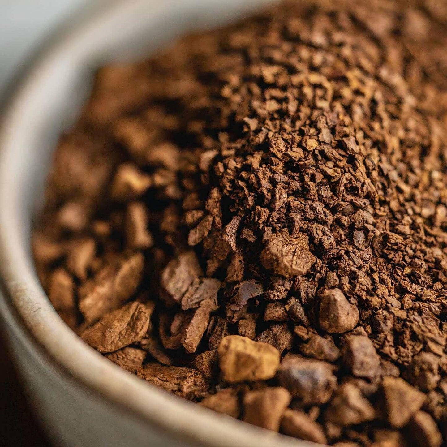 Close-up of ground Naturally Flavored Almond Delight Coffee made with premium Arabica beans in a white bowl.