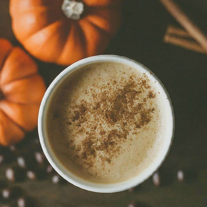 Cozy cup of Pumpkin Spice Flavored Coffee with cinnamon and pumpkins, embodying the warm essence of fall in every sip.