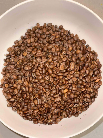 Premium Arabica coffee beans for naturally flavored almond coffee in a white bowl.